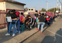 Rezagados llevan sillas y sombrillas ante larga fila para vacunarse