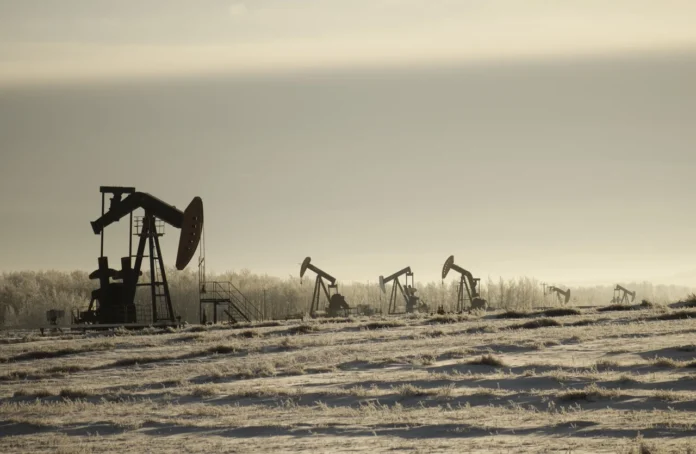field-with-oil-pump-jacks-surrounded-by-greenery-cloudy-sky-sunlight-1